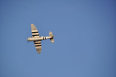 Low angle view of airplane flying against clear blue sky