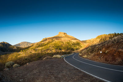 Scenic view of mountain road against clear blue sky