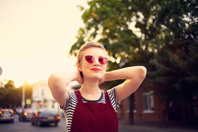 Portrait of young woman wearing sunglasses against trees