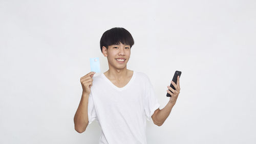 Young man using smart phone against white background