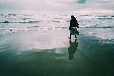 Rear view of woman walking on shore at beach