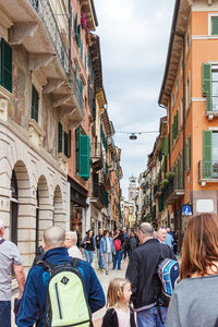 Rear view of people walking on street amidst buildings in city