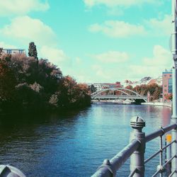 Bridge over river in city against sky