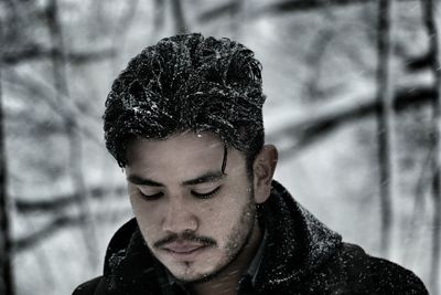 Close-up of man looking down during snowfall