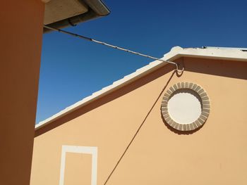 Low angle view of electric lamp against building