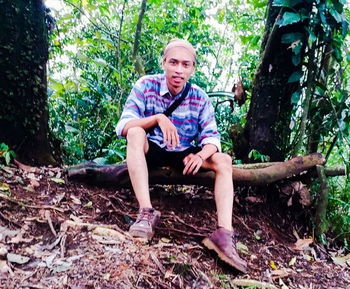 Full length of smiling man sitting in forest