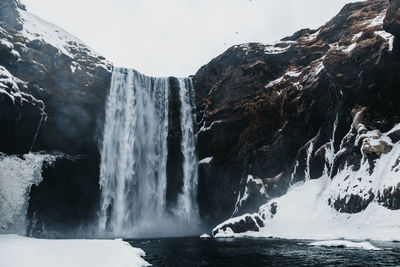 Scenic view of waterfall against sky during winter