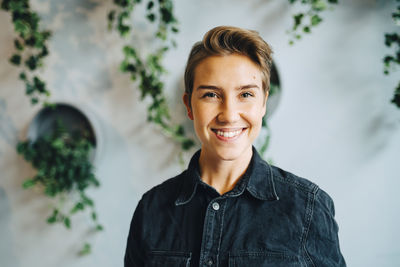 Portrait of young woman standing against wall