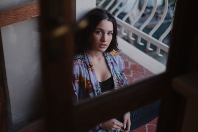 High angle portrait of young woman sitting at home