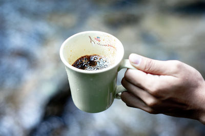 Close-up of hand holding coffee cup