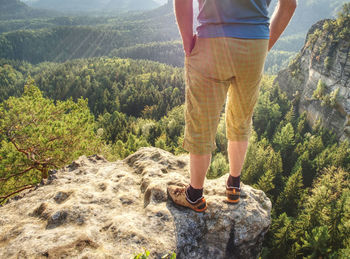 Hiker man stays on the mountain hill during hiking. hker staying on rock and looking down to valley