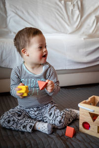 Full length of boy with down syndrome playing on rug at home