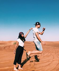 Woman standing on sand dune in desert against clear sky