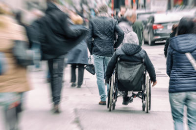 Rear view of people walking on street in city