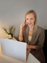 Portrait of a young woman using smart phone and laptop 