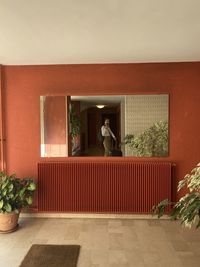 Woman standing by potted plant against building