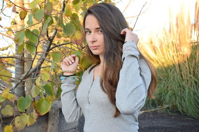 Portrait of beautiful young woman standing against plants