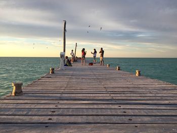 Pier on sea against cloudy sky