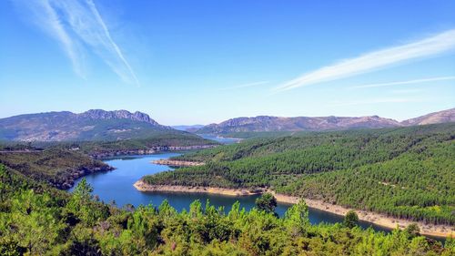 Scenic view of lake and mountains against blue sky