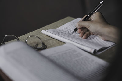 Midsection of woman writing in book