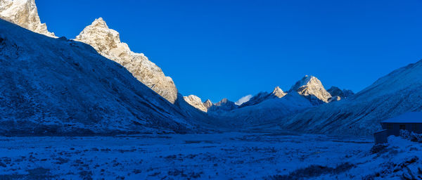 Scenic view of snow covered mountains against clear blue sky