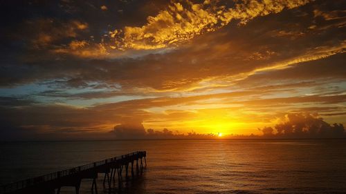 Scenic view of sea against dramatic sky during sunset