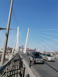 Cars on bridge against clear blue sky