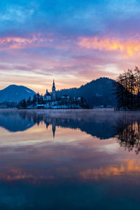 Scenic view of lake against cloudy sky during sunset