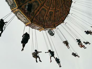Low angle view of people sitting in carousel against sky