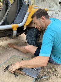 Side view of man working at mini buggy 