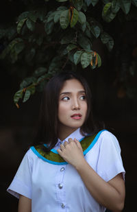 Young woman wearing graduation gown looking away