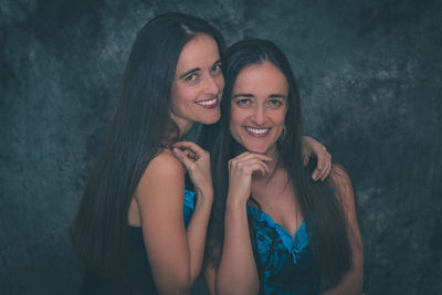 Portrait of smiling sisters against wall