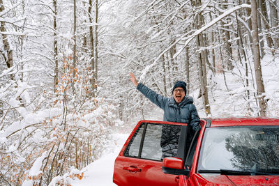 Happy man in red car in winter forest