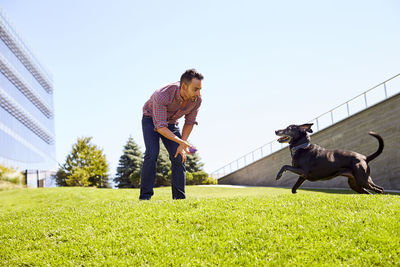 Man with dog on grass against sky