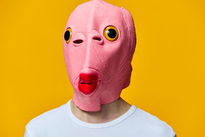 Portrait of man wearing mask against yellow background