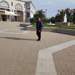 Full length of man standing on footpath in city