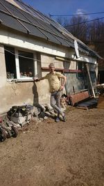 Man standing outside house against sky