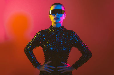 Woman wearing eyeglasses standing against red background