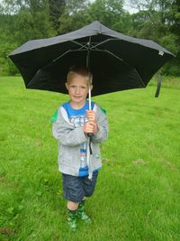 Full length of boy holding umbrella in rain