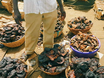 Low section of man with smoked fish for sale at market