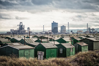 Houses on field by buildings against sky