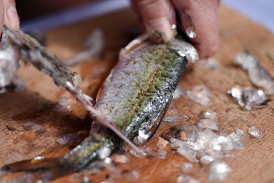 Close-up of man cleaning fish on cutting board