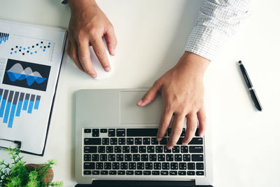 Cropped hands of businessman using laptop on desk