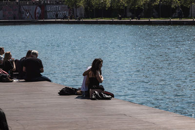 Rear view of people sitting by lake