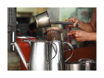 Cropped hands of man preparing tea in kitchen