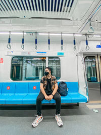 Full length of woman sitting at train