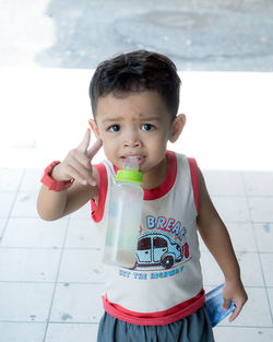 Portrait of boy with milk bottle standing on footpath