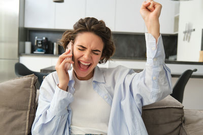 Young woman using mobile phone while sitting at home