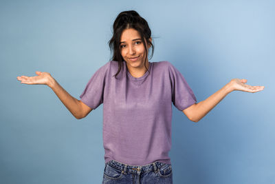 Portrait of smiling young woman standing against blue background