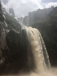 Scenic view of waterfall against sky